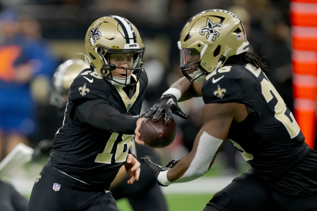 New Orleans Saints quarterback Spencer Rattler (18) hands off to New Orleans Saints running back Kendre Miller (25) during the first half.
