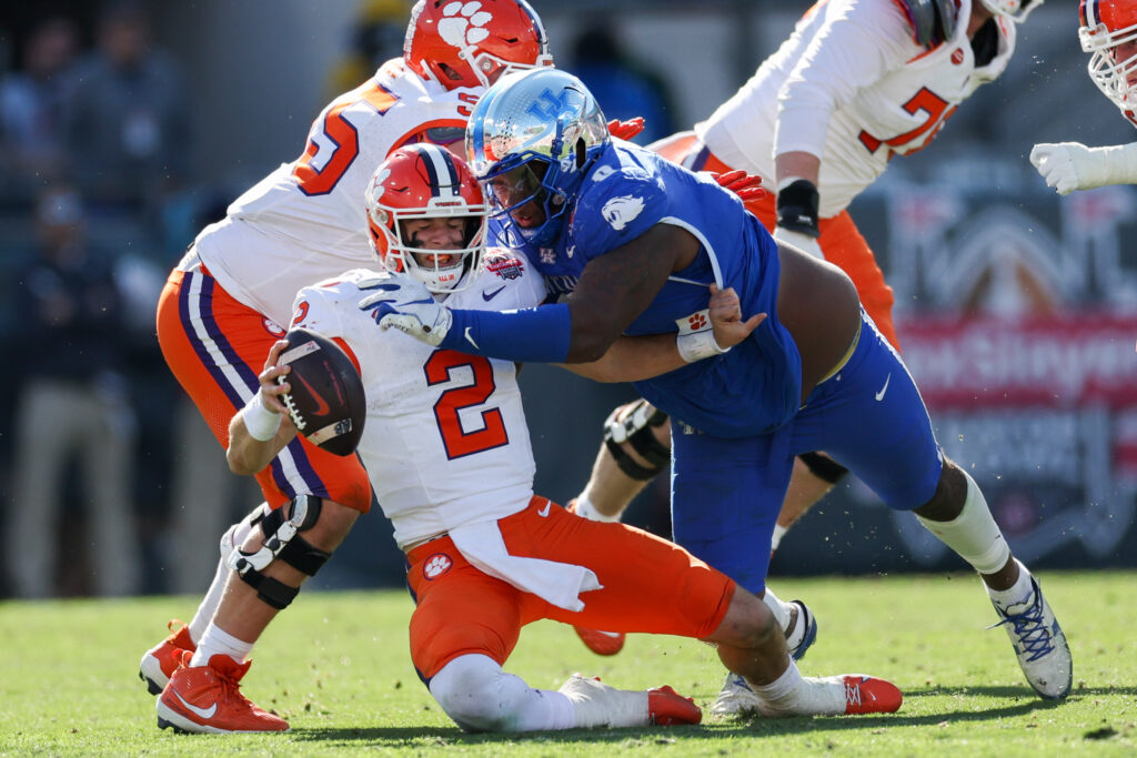 Clemson Tigers quarterback Cade Klubnik (2) is brought down by Kentucky Wildcats defensive lineman Deone Walker (0) in the third quarter during the Gator Bowl at EverBank Stadium. 
