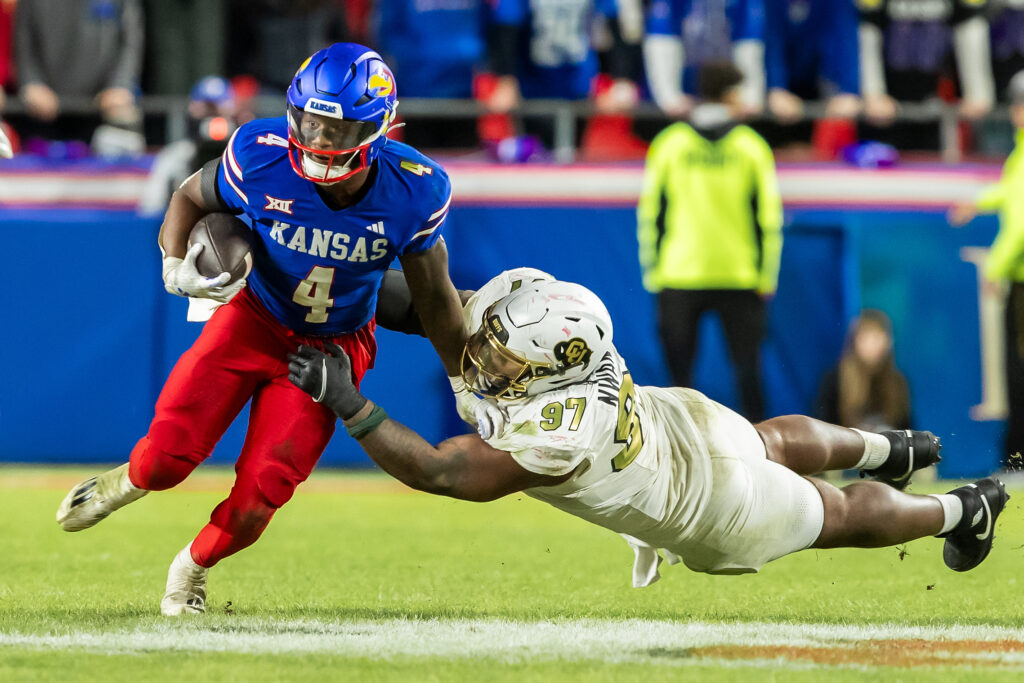 Kansas running back Devin Neal (4) maneuvers past a diving during the Colorado defensive tackle Chidozie Nwankwo (97) at Arrowhead Stadium.
