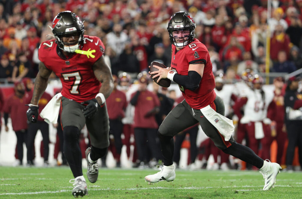 Tampa Bay Buccaneers quarterback Baker Mayfield (6) rolls out behind running back Bucky Irving (7) during the third quarter of a NFC wild card playoff against the Washington Commanders at Raymond James Stadium.