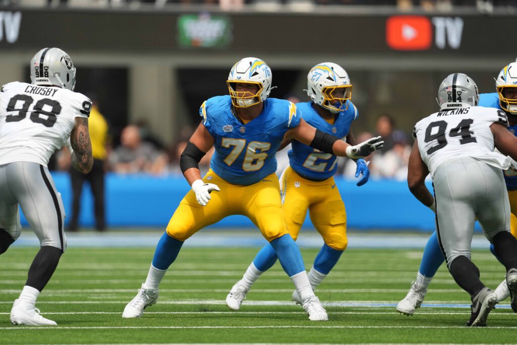 Los Angeles Chargers offensive tackle Joe Alt (76) defends against Las Vegas Raiders defensive end Maxx Crosby (98) and  defensive tackle Christian Wilkins (94) in the first half at SoFi Stadium.